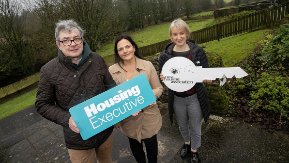A man and two woman holding Housing Executive and Rural Housing Association placards.