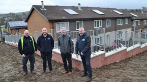 Four men pose in front of the new wall.