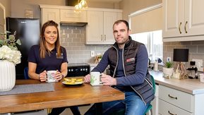 A man and woman sit in their kitchen