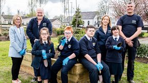 Adults and young people pose at a raised flowerbed.