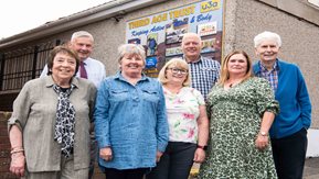 A group of people stand in front of the new East Antrim University of the Third Age sign 