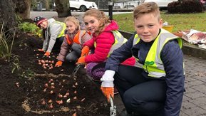 Four children plant bulbs in the ground.