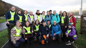 A crowd of people gather together for a photo while on a country walk. 