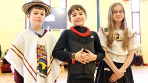 Three school children dressed in colourful clothing.