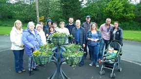 A group of men and women pose with baskets filled with colourful flowers.